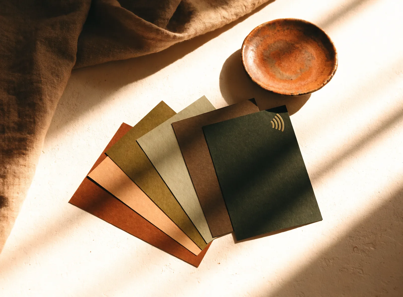 Five Closr Tags fanned out on warm plaster in olive, tan and rust
